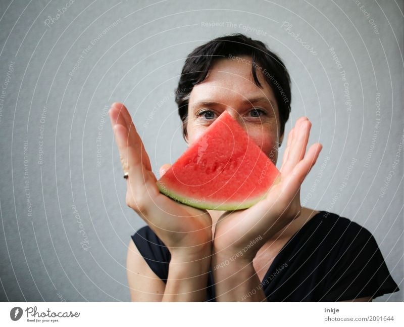 Frau mit Melonenstück vorm Gesicht Frucht Ernährung Bioprodukte Vegetarische Ernährung Fingerfood Lifestyle Stil Freude Freizeit & Hobby Erwachsene Leben Hand 1