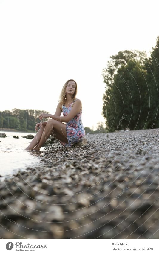 Junge Frau in Sommerkleid sitzt am Rheinufer mit dem Füßen im Fluss Wellness Erholung Ausflug Sommerurlaub Jugendliche Gesicht Beine 18-30 Jahre Erwachsene