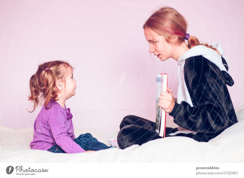 Mädchen, welches die Bilder in einem Buch ihre jüngere Schwester zeigt Lifestyle Bett Kind sprechen Kleinkind 2 Mensch 1-3 Jahre 13-18 Jahre Jugendliche sitzen