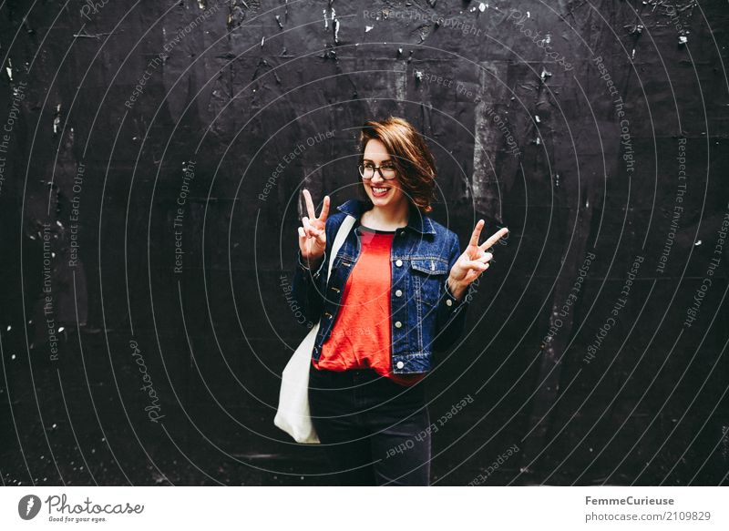 Junge attraktive brünette Frau mit Brille vor der schwarzen Wand zeigt Victory Zeichen mit ihren Händen feminin Junge Frau Jugendliche Erwachsene 1 Mensch