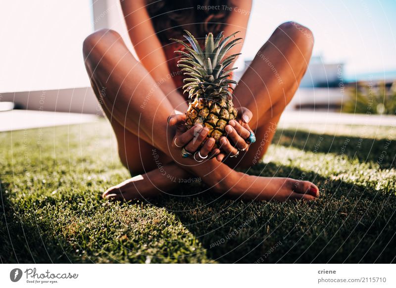 Frau im Badeanzug, der auf dem Gras hält Ananas sitzt Lebensmittel Frucht Ernährung Lifestyle Freude schön Freizeit & Hobby Ferien & Urlaub & Reisen Sommer