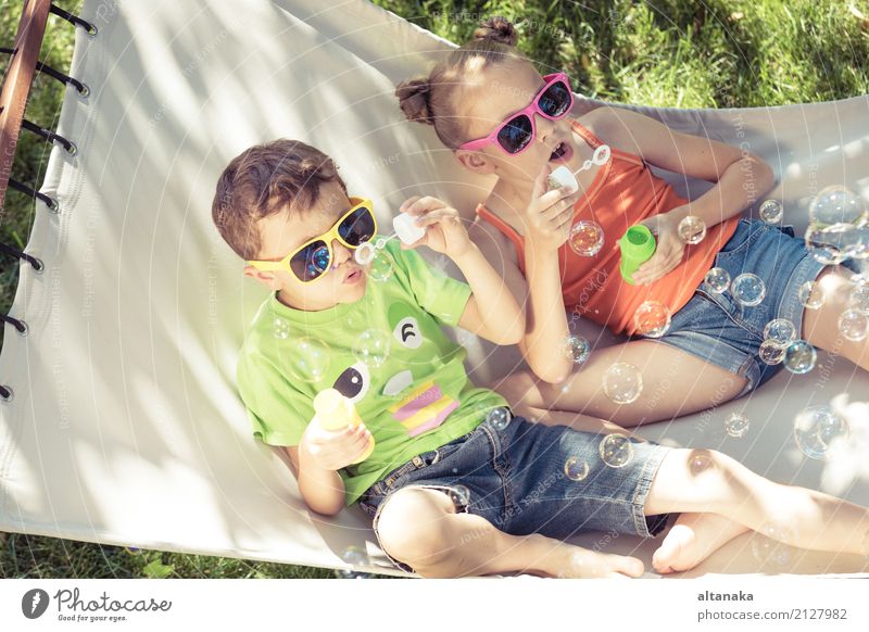 Zwei glückliche Kinder liegen auf einer Hängematte und spielen mit Seifenblasen. Lifestyle Freude Glück schön Erholung Freizeit & Hobby Spielen Freiheit Camping
