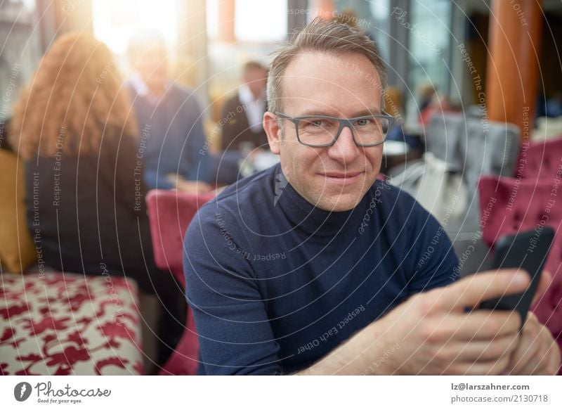 Attraktiver Mann, der in einem Restaurant sitzt Business Telefon Handy PDA Erwachsene 1 Mensch 30-45 Jahre Brille Lächeln sitzen dünn attraktiv Geschäftsmann