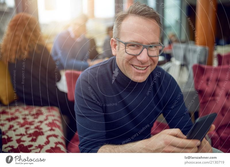 Attraktiver Mann, der in einem Restaurant sitzt Business Telefon Handy PDA Erwachsene 1 Mensch 30-45 Jahre Brille Lächeln sitzen dünn attraktiv Geschäftsmann