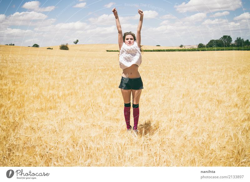 Junge Frau, die auf einem Gebiet des Weizens springt Lifestyle Freude Wellness Leben Ferien & Urlaub & Reisen Sommer Sommerurlaub Sonne Erfolg Mensch feminin
