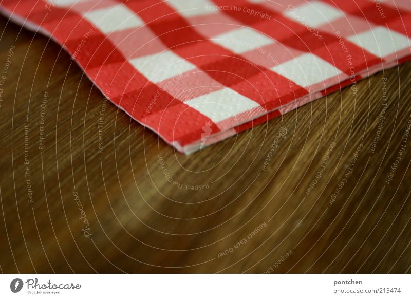 Eine rot-weiß karierte Serviette liegt auf einem Holztisch. Gastronomie Stil Dekoration & Verzierung Kitsch braun Maserung Strukturen & Formen gemütlich