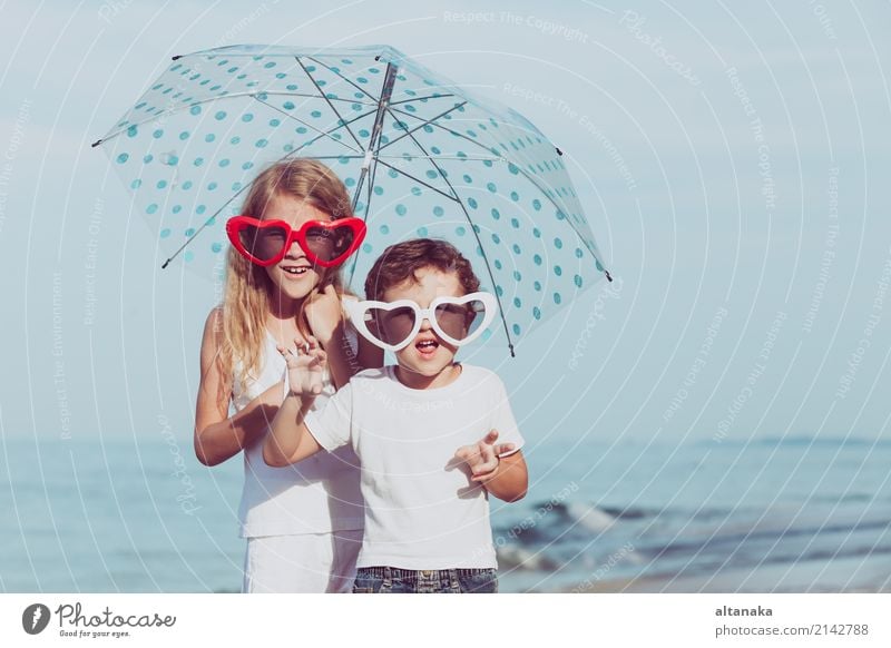 Zwei glückliche Kinder, die zur Tageszeit am Strand stehen. Konzept der freundlichen Familie. Lifestyle Freude Glück schön Erholung Freizeit & Hobby Spielen