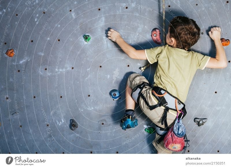 Kleiner Junge klettert auf eine Felswand im Innenbereich. Konzept des Sportlebens. Freude Freizeit & Hobby Spielen Ferien & Urlaub & Reisen Abenteuer Camping