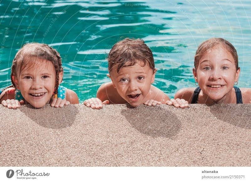 Drei glückliche Kinder spielen auf dem Schwimmbad in der Tageszeit. Menschen, die Spaß im Freien haben. Konzept der freundlichen Geschwister. Lifestyle Freude