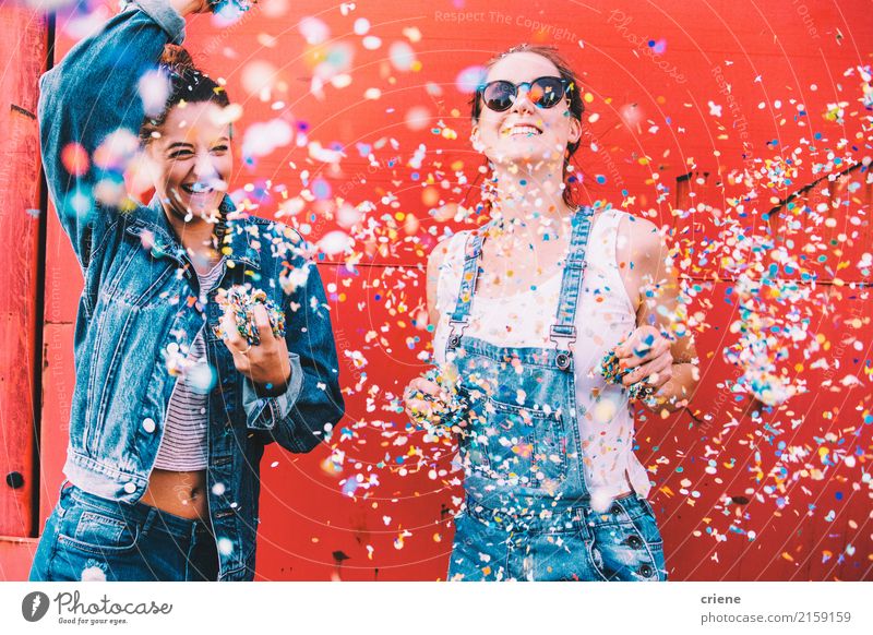 Zwei glückliche junge erwachsene Freunde, die Konfettis tanzen und werfen Lifestyle Freude feminin Junge Frau Jugendliche 2 Mensch 18-30 Jahre Erwachsene