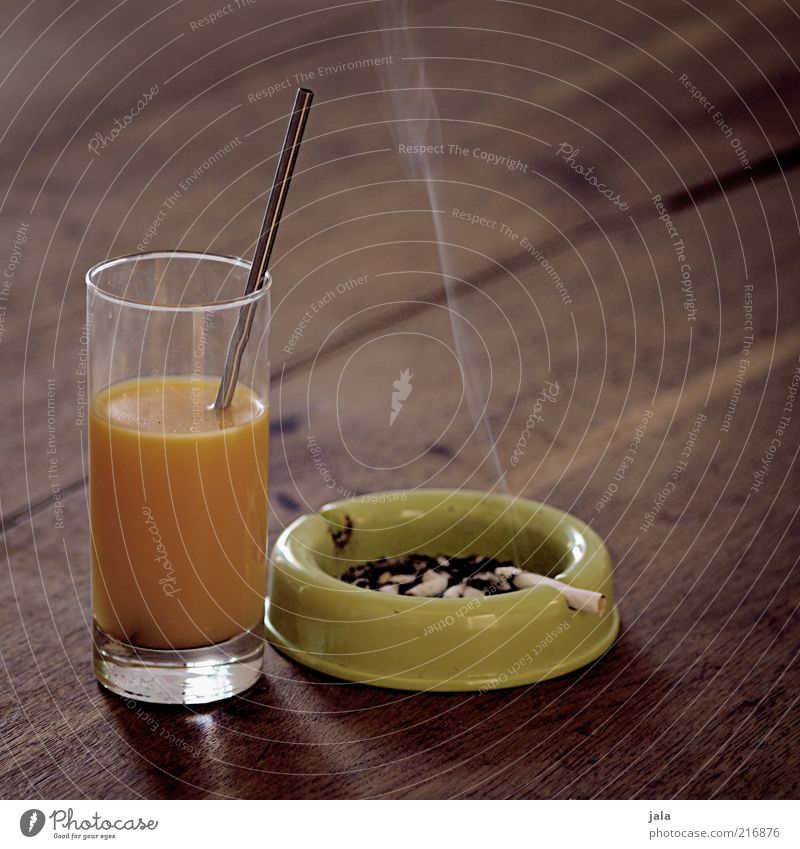 ausgewogene ernährung Lebensmittel Getränk Saft Glas Trinkhalm Aschenbecher Zigarettenasche Holz ungesund Orangensaft Vitamin Nikotin Farbfoto Innenaufnahme