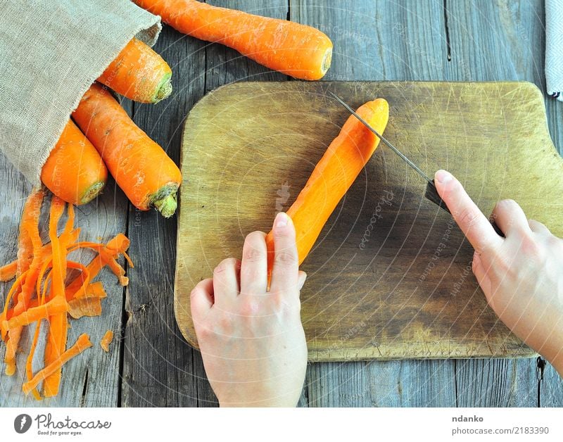 Prozess des Schneidens von frischen Karotten Gemüse Ernährung Vegetarische Ernährung Diät Saft Messer Körper Tisch Arme Hand Natur Holz natürlich Möhre