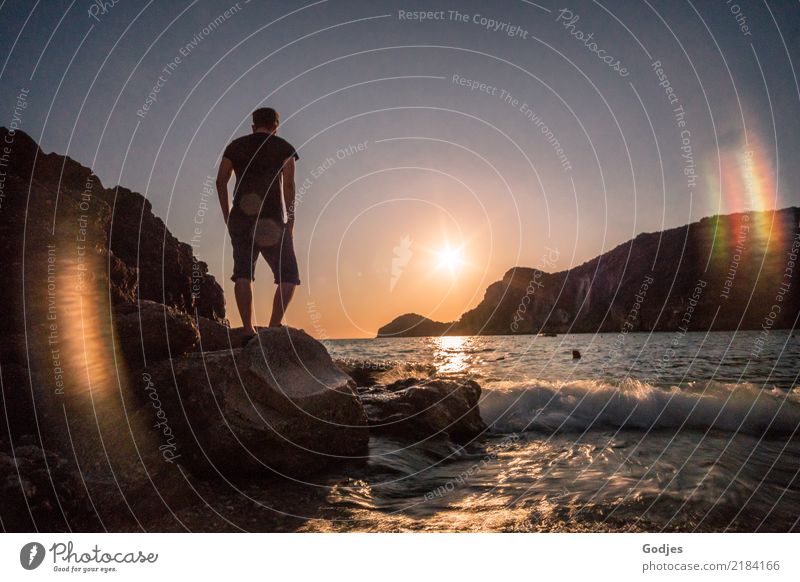 Junger Mann steht auf einem Felsen und blickt aufs Meer in der Abenddämmerung Mensch maskulin Erwachsene 1 30-45 Jahre Natur Wasser Wolkenloser Himmel
