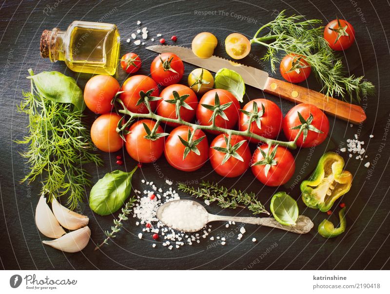 Kirschtomaten, Kräuter und Olivenöl auf einem dunklen Brett Gemüse Vegetarische Ernährung Diät Flasche Löffel Tisch Blatt dunkel frisch hell natürlich grün rot