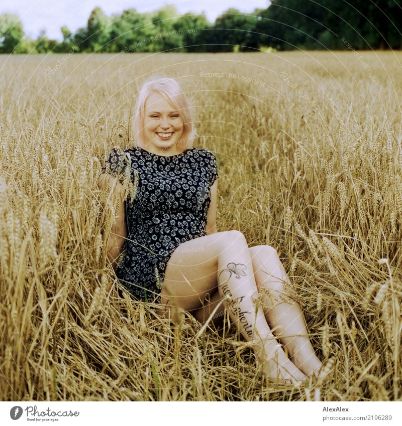 analoges Portrait einer jungen Frau die barfuß im Sommerkleid in einem Roggenfeld sitzt und lächelt schön Leben Wohlgefühl Junge Frau Jugendliche Beine