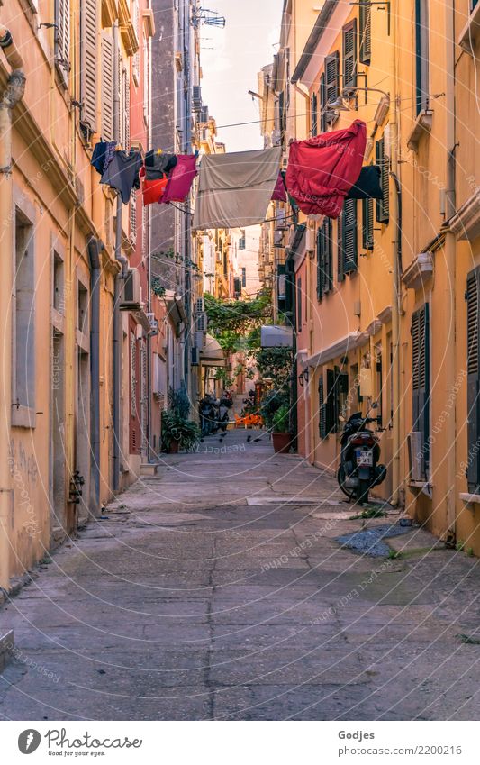Blick in eine Gasse mit Wäsche auf einer Wäscheleine zwischen den Häusern Kérkira Korfu Hauptstadt Altstadt Haus Fassade Motorrad Kleinmotorrad Reinigen