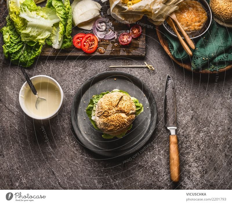 Hausgemachter Burger auf dem Teller mit Messer und Zutaten Lebensmittel Fleisch Käse Gemüse Salat Salatbeilage Brötchen Ernährung Mittagessen Fastfood Geschirr