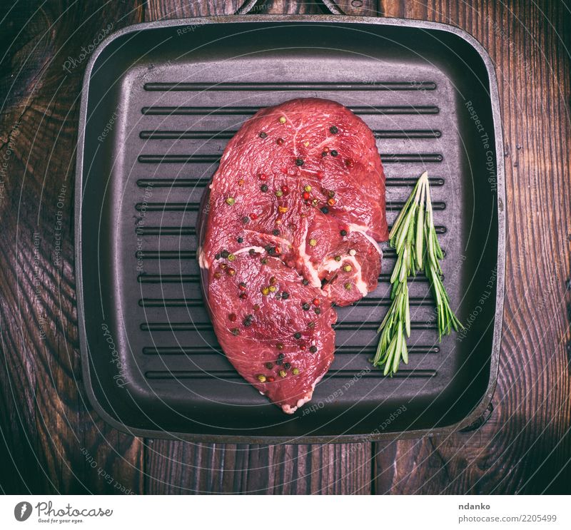 rohes Rindfleisch auf einer schwarzen Bratpfanne Fleisch Kräuter & Gewürze Abendessen Pfanne Tisch Küche Holz Essen frisch oben rot Mahlzeit Barbecue hacken