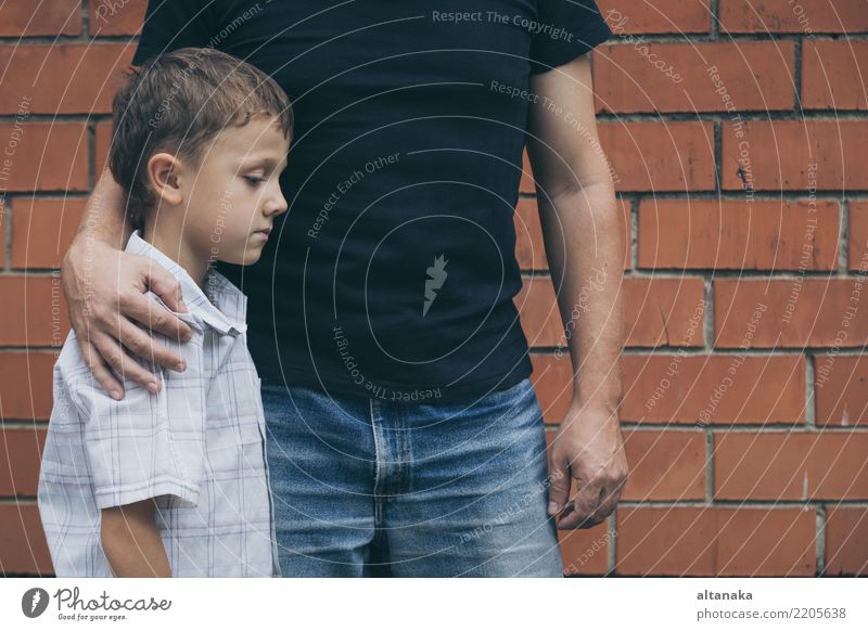 Porträt von jungen traurigen kleinen Jungen und Vater sitzen im Freien an der Tageszeit. Konzept der Traurigkeit. Gesicht Kind Mann Erwachsene Eltern