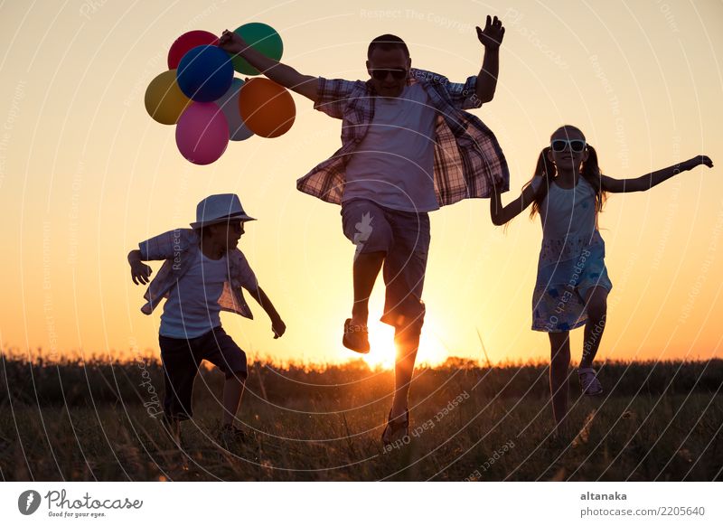 Vater und Kinder rennen zur Zeit des Sonnenuntergangs auf der Straße. Konzept der glücklichen Familie. Lifestyle Freude Glück Freizeit & Hobby