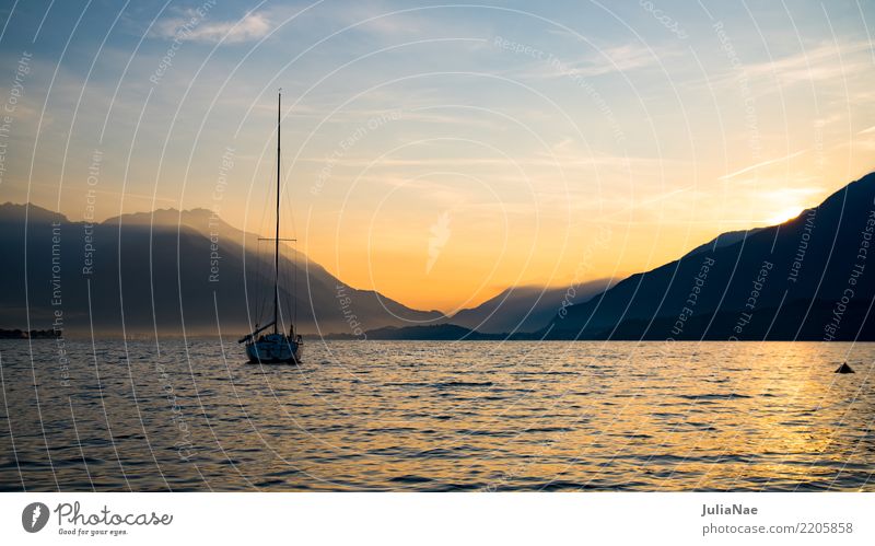 Sonnenaufgang am Comer See mit einem Boot auf dem Wasser lago die como Italien Berge u. Gebirge Alpen Morgen Sonnenstrahlen Morgendämmerung Nebel