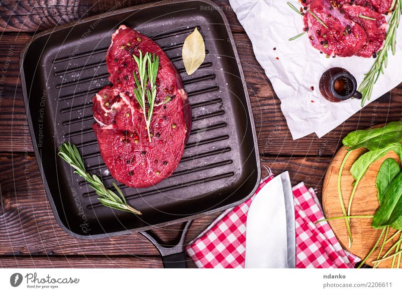 rohes Rindersteak in Gewürzen Fleisch Kräuter & Gewürze Abendessen Tisch Papier Holz frisch grün rot Rindfleisch Blut hacken geschnitten Feinschmecker Zutaten
