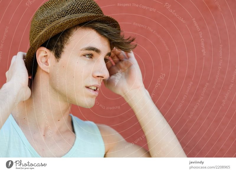 Junger Mann im städtischen Hintergrund, der einen Sonnenhut trägt Lifestyle Stil Glück schön Mensch Erwachsene Straße Mode T-Shirt Hut Coolness frisch trendy