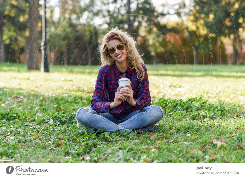 Trinkender Kaffee des blonden Mädchens im Park, der auf Gras sitzt Tee Lifestyle Freude Glück schön Haare & Frisuren Erholung Mensch Frau Erwachsene Natur