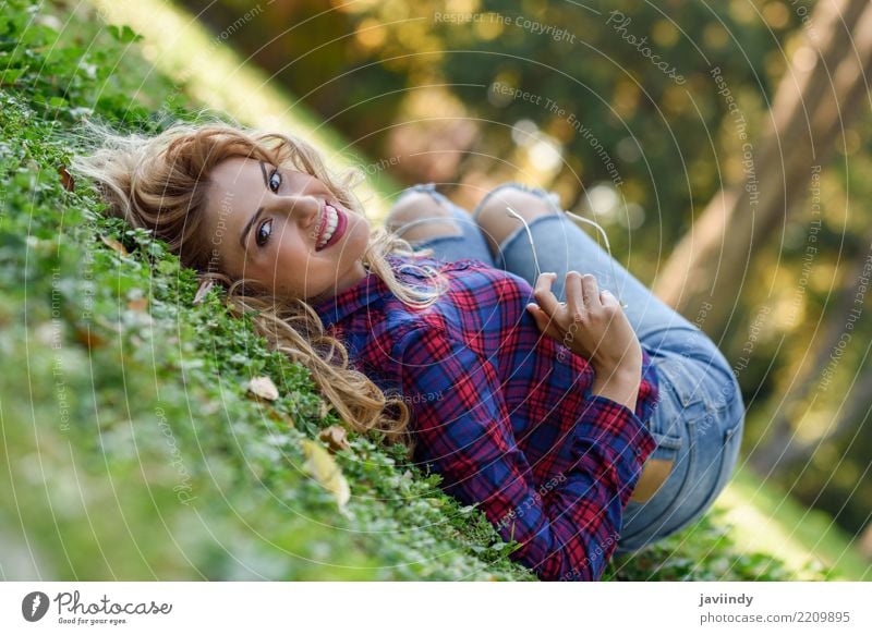 Junge Frau mit dem langen blonden gelockten Haar, das auf Gras legt Lifestyle Freude Glück schön Haare & Frisuren Erholung Mensch feminin Jugendliche Erwachsene