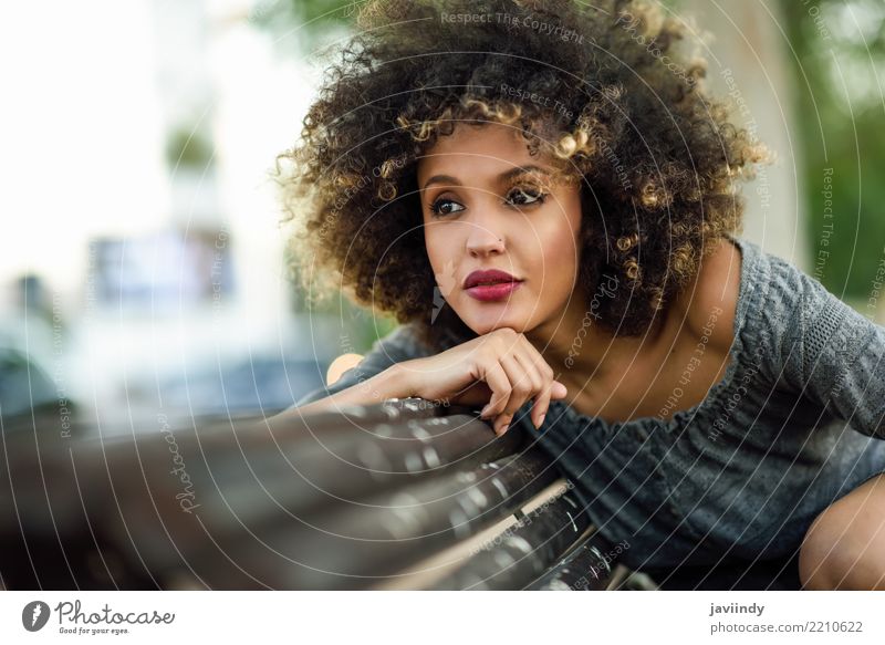 Junge schwarze Frau mit Afrofrisur, die auf einer Bank im städtischen Hintergrund sitzt. Lifestyle Stil Glück schön Haare & Frisuren Gesicht Mensch Erwachsene
