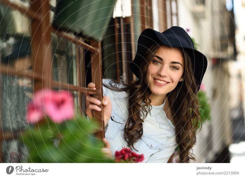 Junge Frau, die mit Hut nahe einem Fenster lächelt Lifestyle elegant Stil Glück schön Haare & Frisuren Gesicht Mensch Erwachsene Straße Mode Hemd brünett