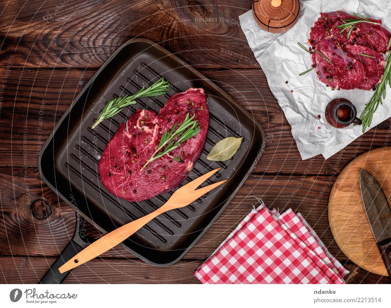 frisches Rindersteak mit Rosmarin Fleisch Kräuter & Gewürze Abendessen Gabel Tisch Papier Holz grün rot Rindfleisch Blut hacken geschnitten Feinschmecker