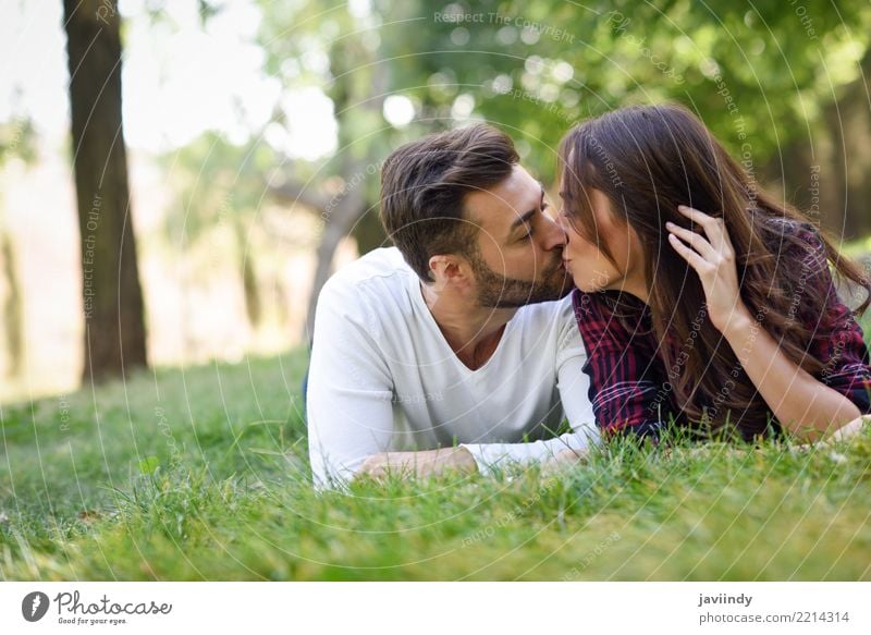 Schöne junge Paare, die auf Gras in einem städtischen Park küssen Lifestyle Freude Glück schön Sommer Frau Erwachsene Mann 18-30 Jahre Jugendliche 30-45 Jahre