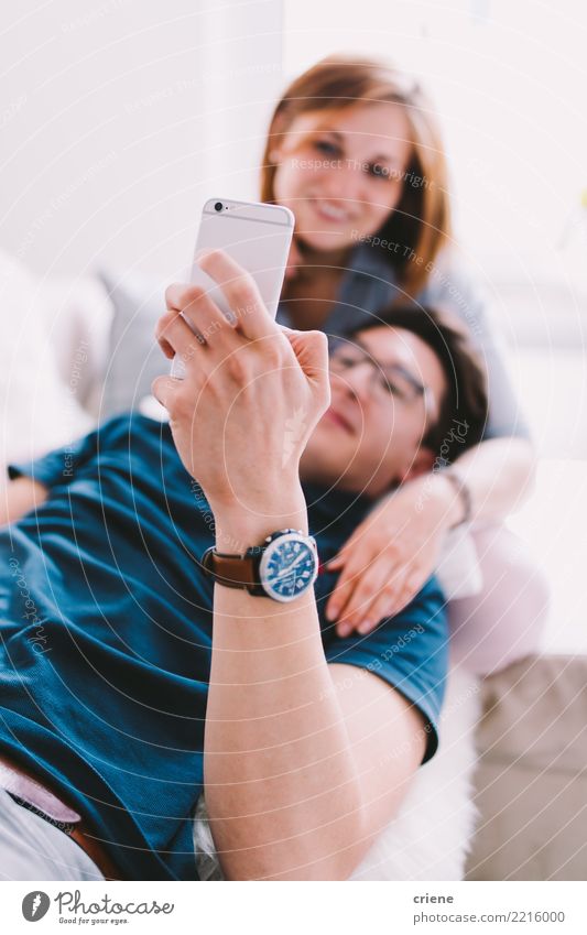 Paare, die online zu Hause auf Smartphone durchstöbern Lifestyle Erholung Freizeit & Hobby Sofa sprechen Telefon Technik & Technologie Frau Erwachsene Mann