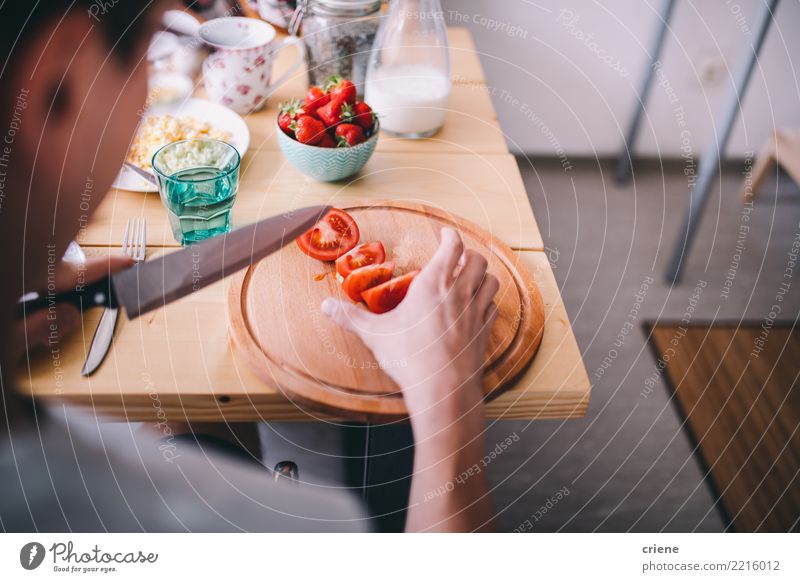 Mann, der morgens Tomaten am Frühstückstisch schneidet Gemüse Essen Diät Gesunde Ernährung Haus Tisch Küche Erwachsene Jugendliche sitzen Messer im Innenbereich