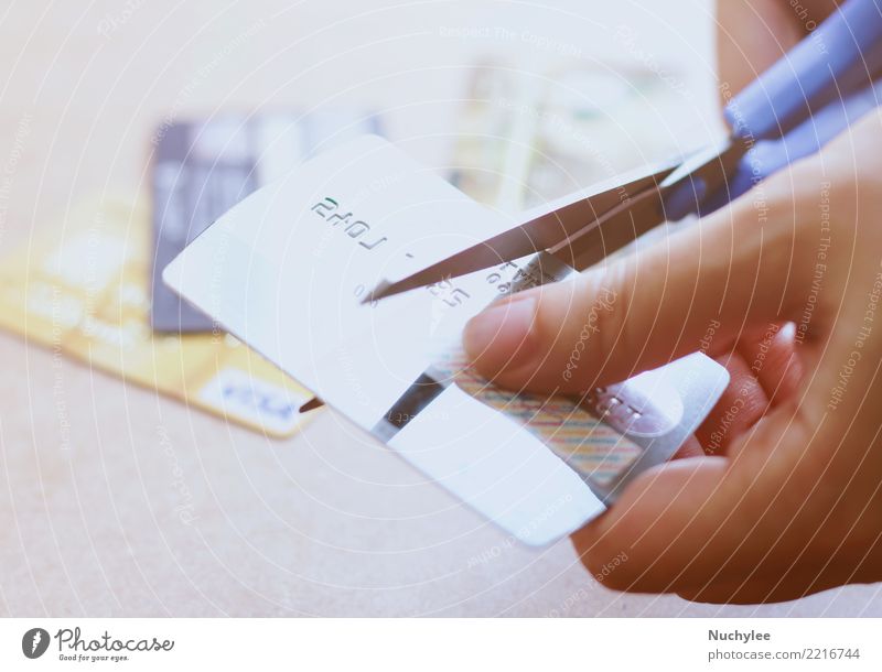 Hand, die Kreditkarte mit Scheren auf Tabelle schneidet Tisch Wirtschaft Kapitalwirtschaft Geldinstitut Frau Erwachsene Mann Finger Kunststoff Armut Sicherheit