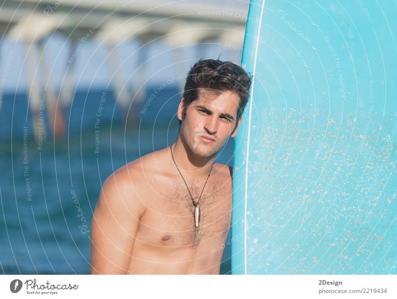 Junger attraktiver Surfer, der sein Surfbrett am Strand hält Lifestyle Freude Ferien & Urlaub & Reisen Sommer Meer Wellen Sport Mann Erwachsene Jugendliche