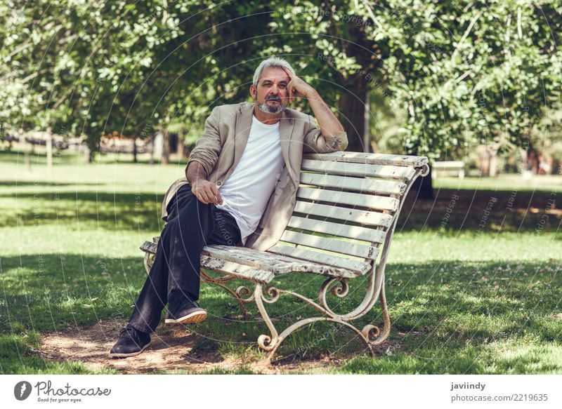 Nachdenklicher reifer Mann, der auf einer Bank in einem städtischen Park sitzt. Lifestyle Glück Ruhestand Mensch Erwachsene Männlicher Senior 1 45-60 Jahre