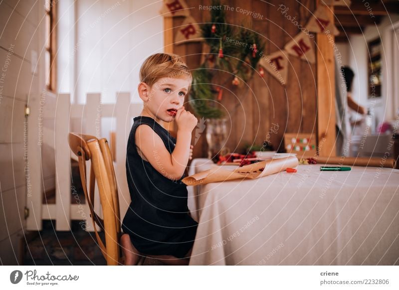 Kaukasisches kleines Kleinkind, das Weihnachtssüßigkeit isst Essen Winter Tisch Wohnzimmer Weihnachten & Advent Kind Junge 1-3 Jahre 3-8 Jahre Kindheit