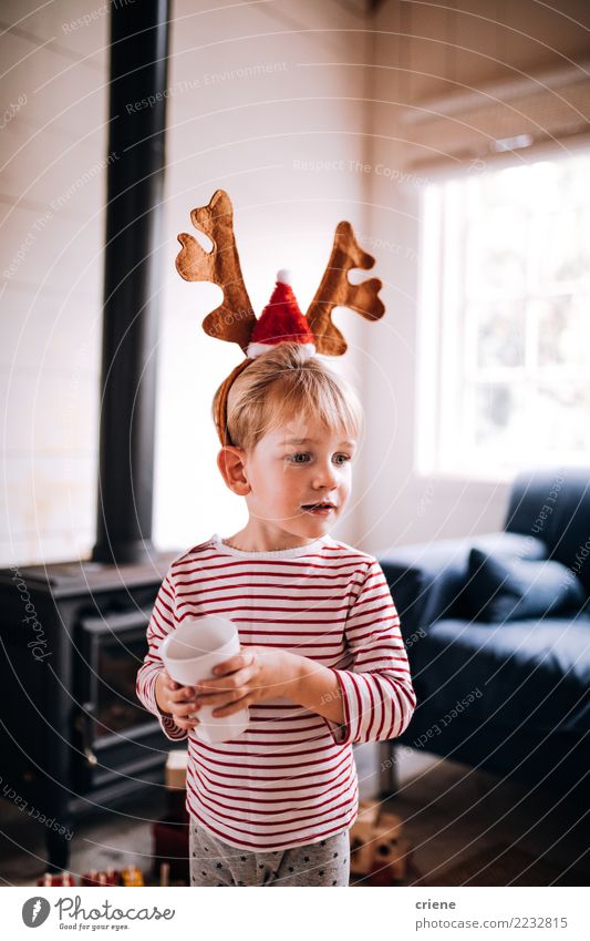 Tragendes Renohrskostüm des netten Kleinkindes am Weihnachtstag trinken Lifestyle Freude Glück Winter Haus Wohnzimmer Weihnachten & Advent Kind Wärme Lächeln