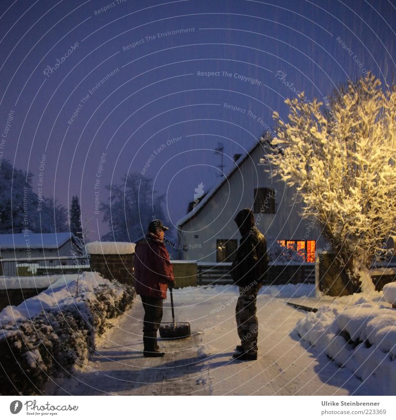 Vater schippt am Abend Schnee in der Einfahrt, Sohn schaut zu Winter Mensch maskulin Junger Mann Jugendliche 2 Eis Frost Baum Einfamilienhaus Wege & Pfade Jacke