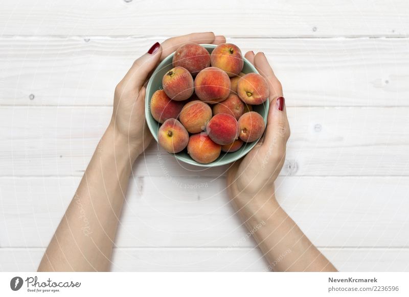 Weibliche Hände, die eine Schüssel Pfirsiche halten Lebensmittel Frucht Ernährung Essen Frühstück Mittagessen Abendessen Picknick Bioprodukte