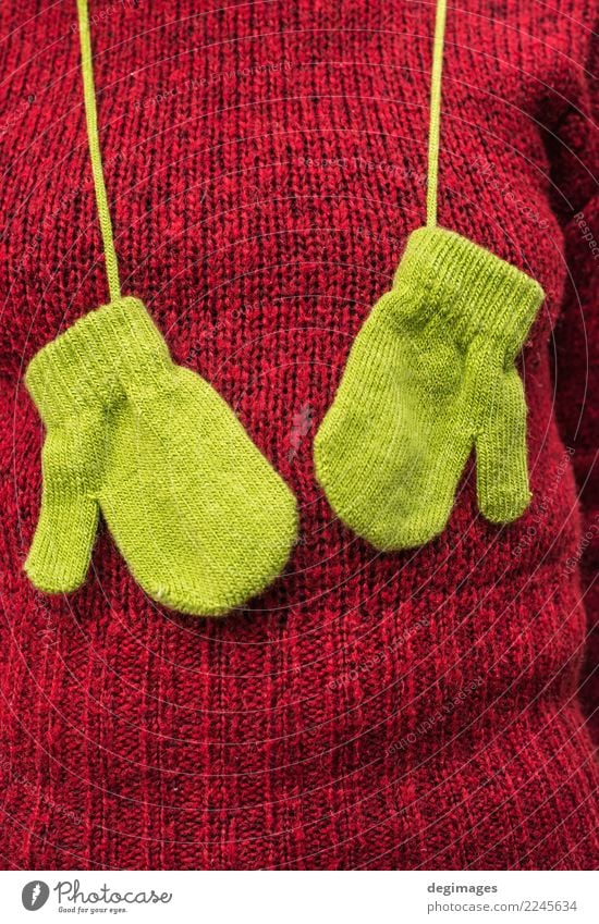 Grüne Handschuhe des Winters auf roter Strickjacke der Frauen Erwachsene Herbst Wärme Mode Bekleidung Pullover Schal Hut natürlich grün Farbe Hintergrund Wolle