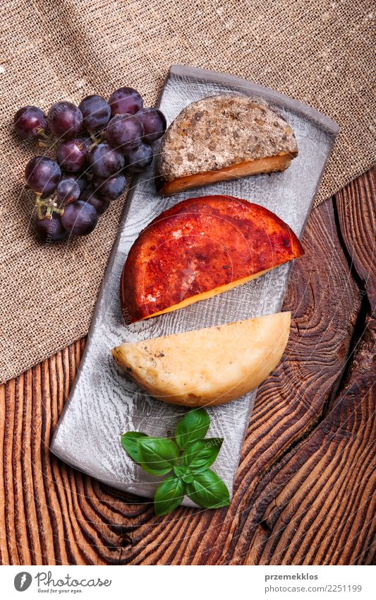 Käse und schwarze Trauben auf handgemachter Tonwarenplatte Lebensmittel Milcherzeugnisse Frucht Teller Tisch Holz Rost frisch lecker oben Keramik