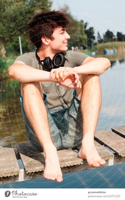 Junger lächelnder Junge, der auf Anlegestelle über dem See sitzt Lifestyle Freude Glück Erholung Freizeit & Hobby Ferien & Urlaub & Reisen Sommer Sommerurlaub