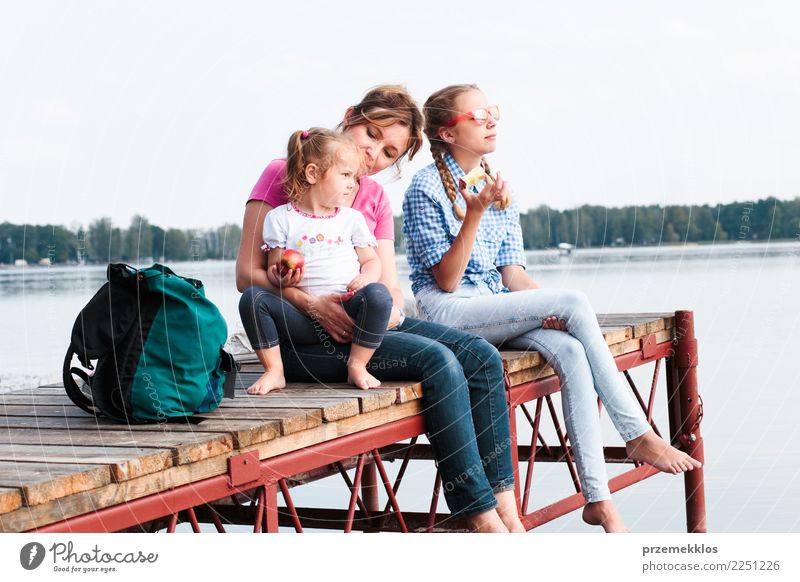 Eine Familie, die gemeinsam Urlaub macht und an einem sonnigen Sommertag einen Imbiss am Steg über dem See einnimmt Freude Glück Erholung Freizeit & Hobby