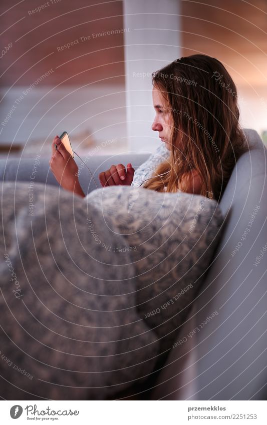 Aufpassender Film des Mädchens online auf dem Smartphone, der zu Hause auf Bett sitzt Lifestyle Freizeit & Hobby Kind Telefon Handy PDA Technik & Technologie