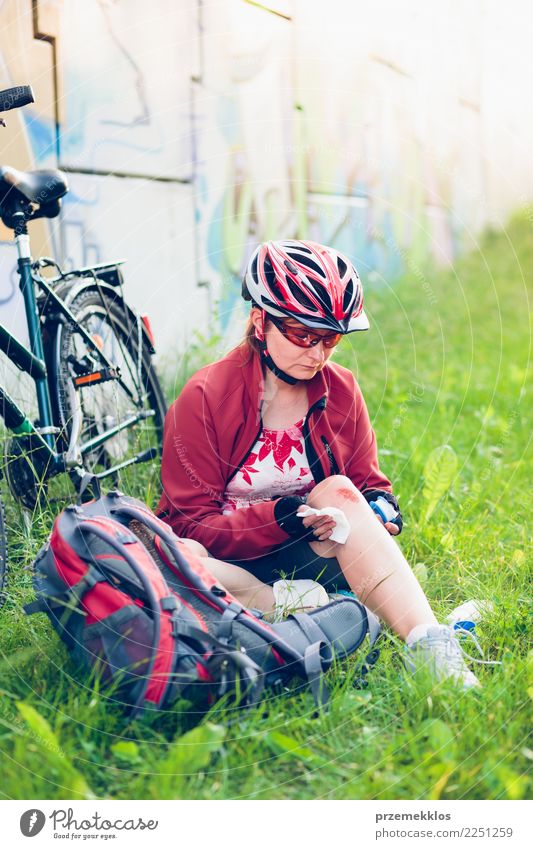 Frau, die die Wunde auf ihrem Knie mit Medizin im Spray ankleidet Lifestyle Ferien & Urlaub & Reisen Sommer Sport Fahrradfahren Mensch Erwachsene Gras Schmerz