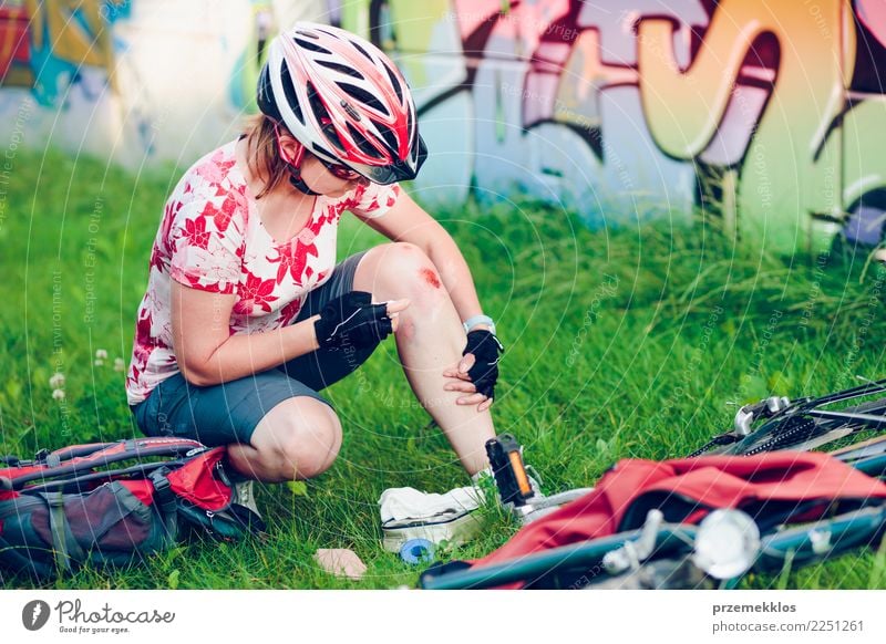 Frau, die die Wunde auf ihrem Knie mit Medizin im Spray ankleidet Lifestyle Ferien & Urlaub & Reisen Sommer Fahrradfahren Mensch Erwachsene 1 Gras Schmerz