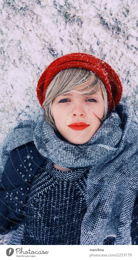 Junge Frau, die sich über dem Schnee am Winter hinlegt Lifestyle Stil schön Haut Gesicht Wellness Ferien & Urlaub & Reisen Abenteuer Winterurlaub Mensch feminin